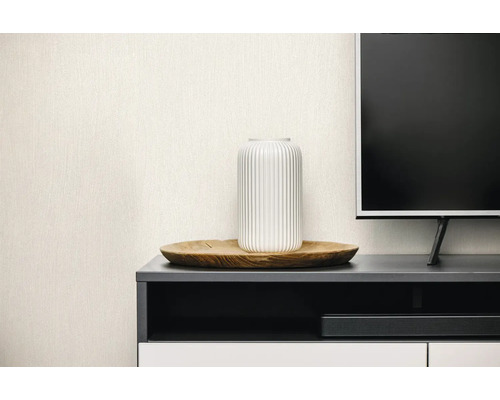 Lichtbeige vliesbehang met fijne linnenstructuur in een moderne woonkamer achter een tv-meubel met decoratie.