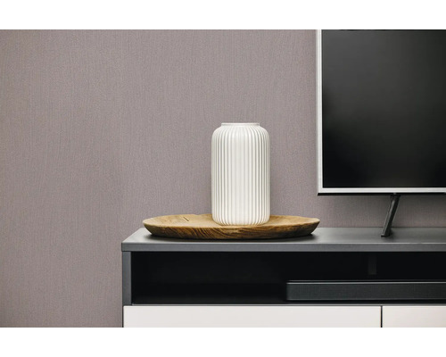 Gestructureerd behang met verticaal patroon in een moderne woonkamer achter een tv-meubel met vaas en houten schaal.