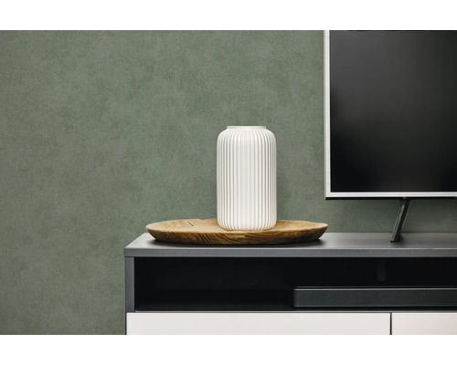 Gestructureerd behang in donkergroen achter een dressoir met witte vaas en televisie.