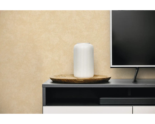 Vliesbehang met structuur in beige achter een dressoir met decoratie en televisie.