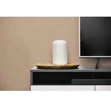 Beige vliesbehang met linnenstructuur op een muur in een moderne woonkamer achter een dressoir.