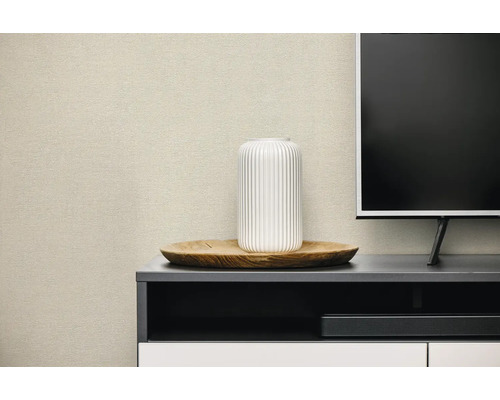 Behang met textuur in een moderne woonkamer achter een televisiekast met decoratieve schaal en vaas.