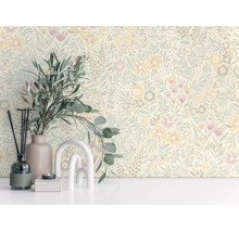 Vliesbehang met bloemen- en bladerpatroon in een lichte kamerinrichting met een vaas en eucalyptus takken.