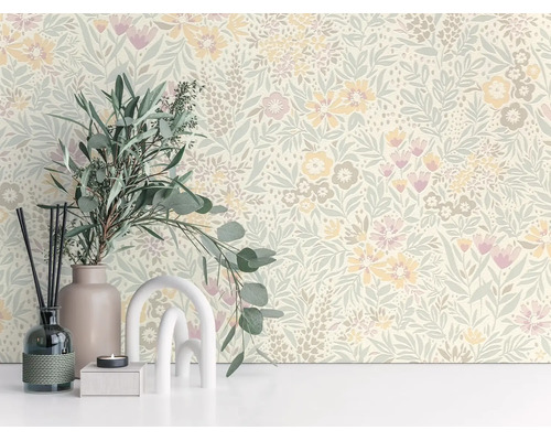 Vliesbehang met bloemen- en bladerpatroon in een lichte kamerinrichting met een vaas en eucalyptus takken.