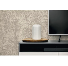 Licht ingerichte woonkamer met vliesbehang met boommotief achter een dressoir met televisie, houten schaal en geribbelde vaas.
