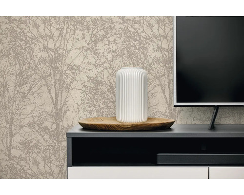 Licht ingerichte woonkamer met vliesbehang met boommotief achter een dressoir met televisie, houten schaal en geribbelde vaas.