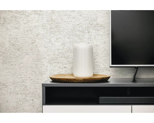 Gestructureerd behang met linnenlook achter een donker dressoir met een witte vaas op een houten dienblad en een televisie.