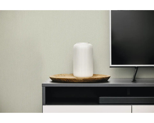 Gestructureerd vliesbehang in een moderne woonkamer achter een tv-meubel met een witte vaas op een houten dienblad.