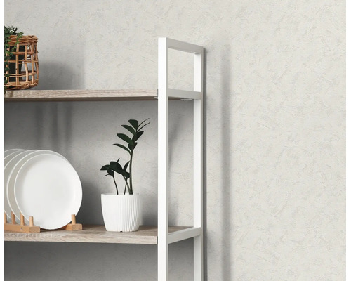 Lichtgrijs vliesbehang met fijne structuur achter een wit rek met houten planken, borden en een plant.