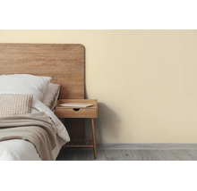 Licht ingerichte slaapkamer met beige muur, houten bed en bijpassend nachtkastje op grijze vloer.