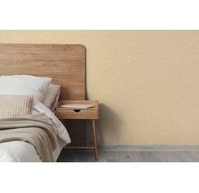 Beige behang met textuur in een licht ingerichte slaapkamer naast een bed met houten hoofdbord en een nachtkastje.
