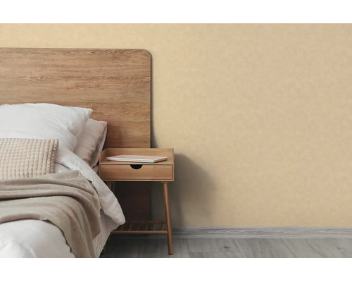 Beige behang met textuur in een licht ingerichte slaapkamer naast een bed met houten hoofdbord en een nachtkastje.
