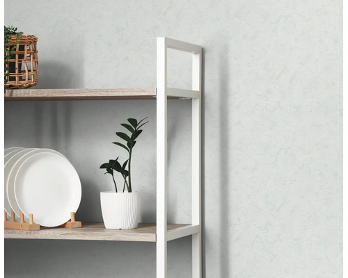 Modern open rek met wit metalen frame en houten planken, gedecoreerd met borden en planten tegen een muur met textuur.