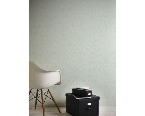Behang met structuur op een muur in een lichte kamer met een moderne witte stoel en zwarte dozen.