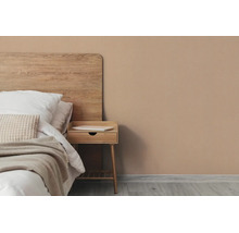 Helder ingerichte slaapkamer met houten bed, houten nachtkastje en muurverf in aardetint.