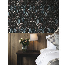 Vliesbehang met een fijn bloemenpatroon in een slaapkamer boven een houten lambrisering met een nachtkastje en lamp.