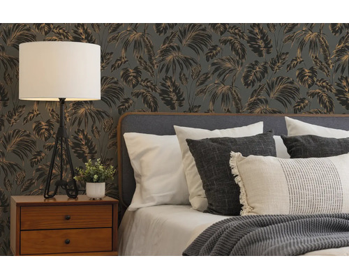 Moderne slaapkamer met tropisch behang, houten nachtkastje, een driepoot tafellamp en een bed met kussens en gebreide deken.