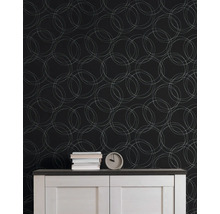Behang met geometrisch patroon van overlappende cirkels achter een dressoir met boeken en een klok in een georganiseerde kamer.