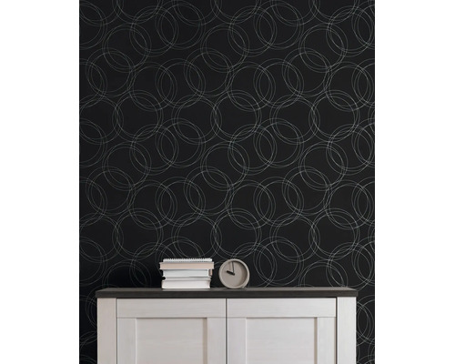 Behang met geometrisch patroon van overlappende cirkels achter een dressoir met boeken en een klok in een georganiseerde kamer.