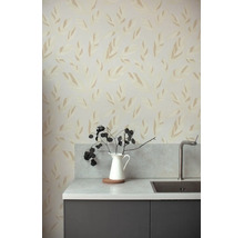 Vliesbehang met gestileerd bladerpatroon in een moderne keuken met werkblad in steenlook, roestvrijstalen spoelbak en een donker kastje.
