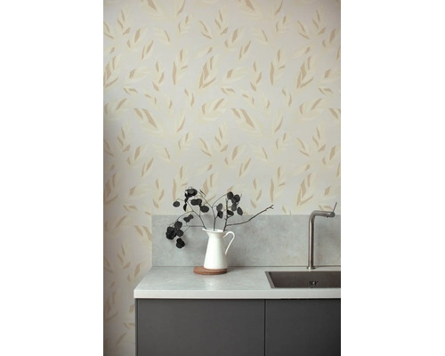 Vliesbehang met gestileerd bladerpatroon in een moderne keuken met werkblad in steenlook, roestvrijstalen spoelbak en een donker kastje.