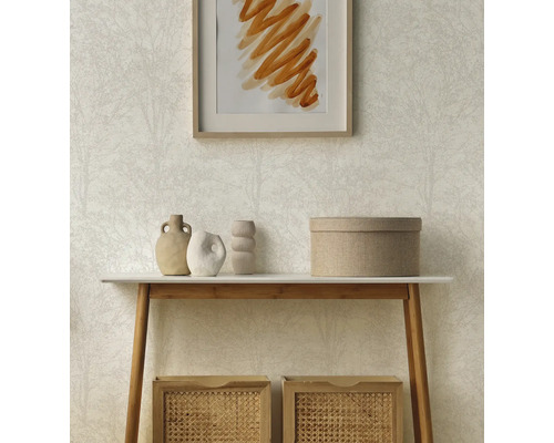 Lichtbeige vliesbehang met subtiel boompatroon achter een houten consoletafel met decoratieve vazen en gevlochten manden.