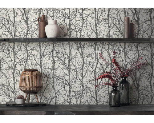 Vliesbehang met zwart boom- en takkenpatroon op een lichte achtergrond, gedecoreerd met een donkere wandplank, vazen, kaarsen en een houten lantaarn.