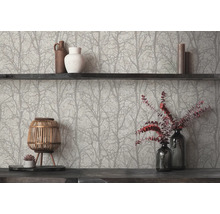 Vliesbehang met boom- en takkenpatroon achter een donkere houten plank met vazen, kaarsen en een decoratieve houten lantaarn.