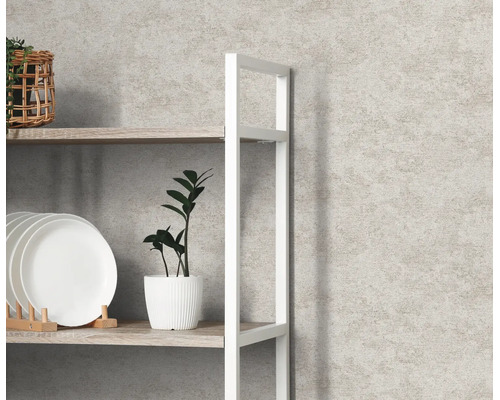Gestructureerd vliesbehang met steenlook achter een wit rek met servies en een plant in een lichte kamer.