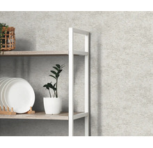 Vliesbehang in betonlook met fijne structuur op een wand achter een rek met decoratie.