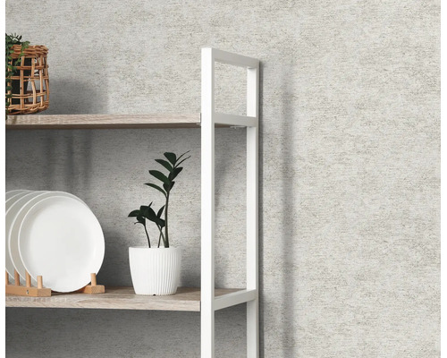 Vliesbehang in betonlook met fijne structuur op een wand achter een rek met decoratie.