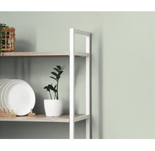 Wandrek met wit metalen frame en houten planken, gedecoreerd met witte borden, een kamerplant en een gevlochten mand.