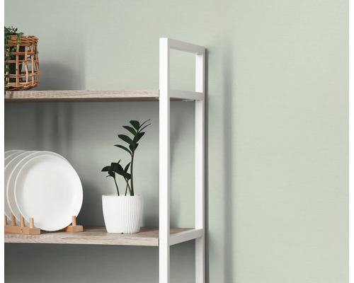 Wandrek met wit metalen frame en houten planken, gedecoreerd met witte borden, een kamerplant en een gevlochten mand.