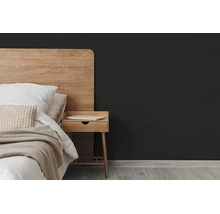 Donkergrijze muur in een moderne slaapkamer met houten bed, nachtkastje en lichte houten vloer.