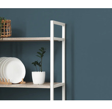 Moderne open stellingkast met wit metalen frame en houten planken, gedecoreerd met borden, een kamerplant en een mand.