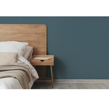 Moderne slaapkamer met een donkerblauwgroene muur, een houten hoofdbord en een bijpassend houten nachtkastje.