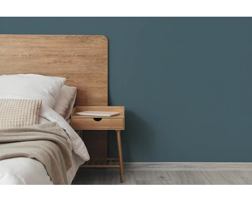Moderne slaapkamer met een donkerblauwgroene muur, een houten hoofdbord en een bijpassend houten nachtkastje.
