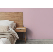 Slaapkamer met lila muur, bed met houten hoofdbord en houten nachtkastje op een lichte houten vloer.