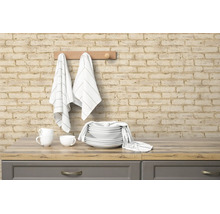 Vliesbehang in baksteenlook op een keukenmuur met hangende theedoeken en servies op een aanrechtblad in houtlook.