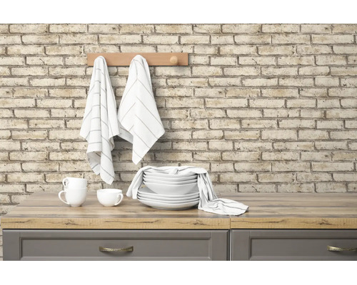 Lichte, georganiseerde keuken met muur in baksteenlook, houten werkblad, wit servies en keukendoeken aan een houten kapstok.