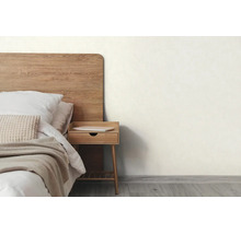 Lichte slaapkamer met houten bed, bijpassend nachtkastje, een lichte muur en vloer met houtlook.