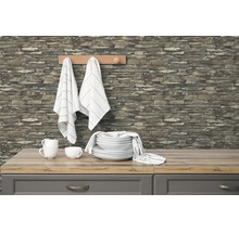 Moderne keuken met vliesbehang in steenoptiek op de muur, gecombineerd met een licht werkblad in houtoptiek en wit keramisch servies.