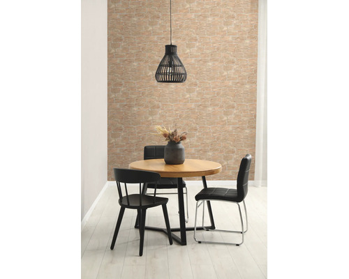 Lichte woonkamer met behang in steenlook, ronde houten tafel, zwarte stoelen en een hanglamp.