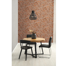 Woonkamer met behang in baksteenlook, ronde houten tafel en zwarte stoelen.