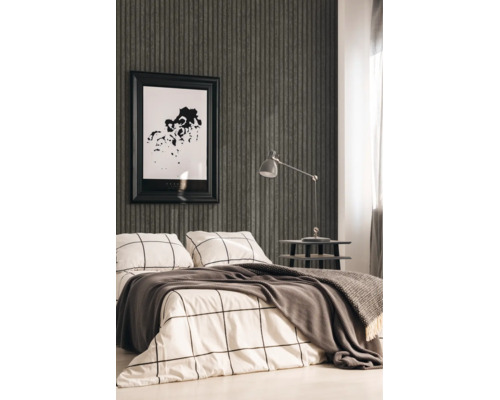 Moderne slaapkamer met donkergrijs behang met verticale strepen, beddengoed met ruitpatroon en een grijze bureaulamp op een bijzettafel.