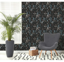 Moderne woonkamer met vliesbehang met bloemenpatroon, een grijze fauteuil, een grote kamerplant en een gedessineerd tapijt.
