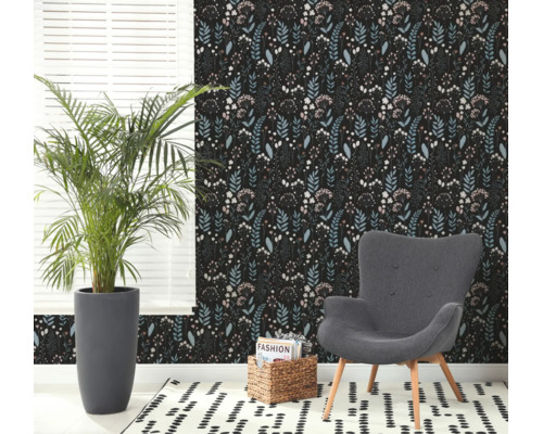 Moderne woonkamer met vliesbehang met bloemenpatroon, een grijze fauteuil, een grote kamerplant en een gedessineerd tapijt.