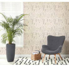 Lichte kamer met botanisch vliesbehang, grijze fauteuil, grote kamerplant en een gedessineerd vloerkleed bij een raam.
