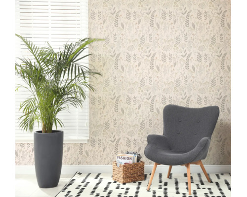 Lichte kamer met botanisch vliesbehang, grijze fauteuil, grote kamerplant en een gedessineerd vloerkleed bij een raam.