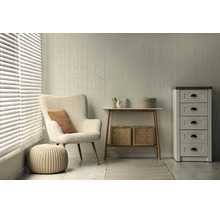 Lichte woonkamer met gestructureerd behang met bamboepatroon, witte teddy fauteuil, gebreide poef, houten consoletafel en witte ladekast.